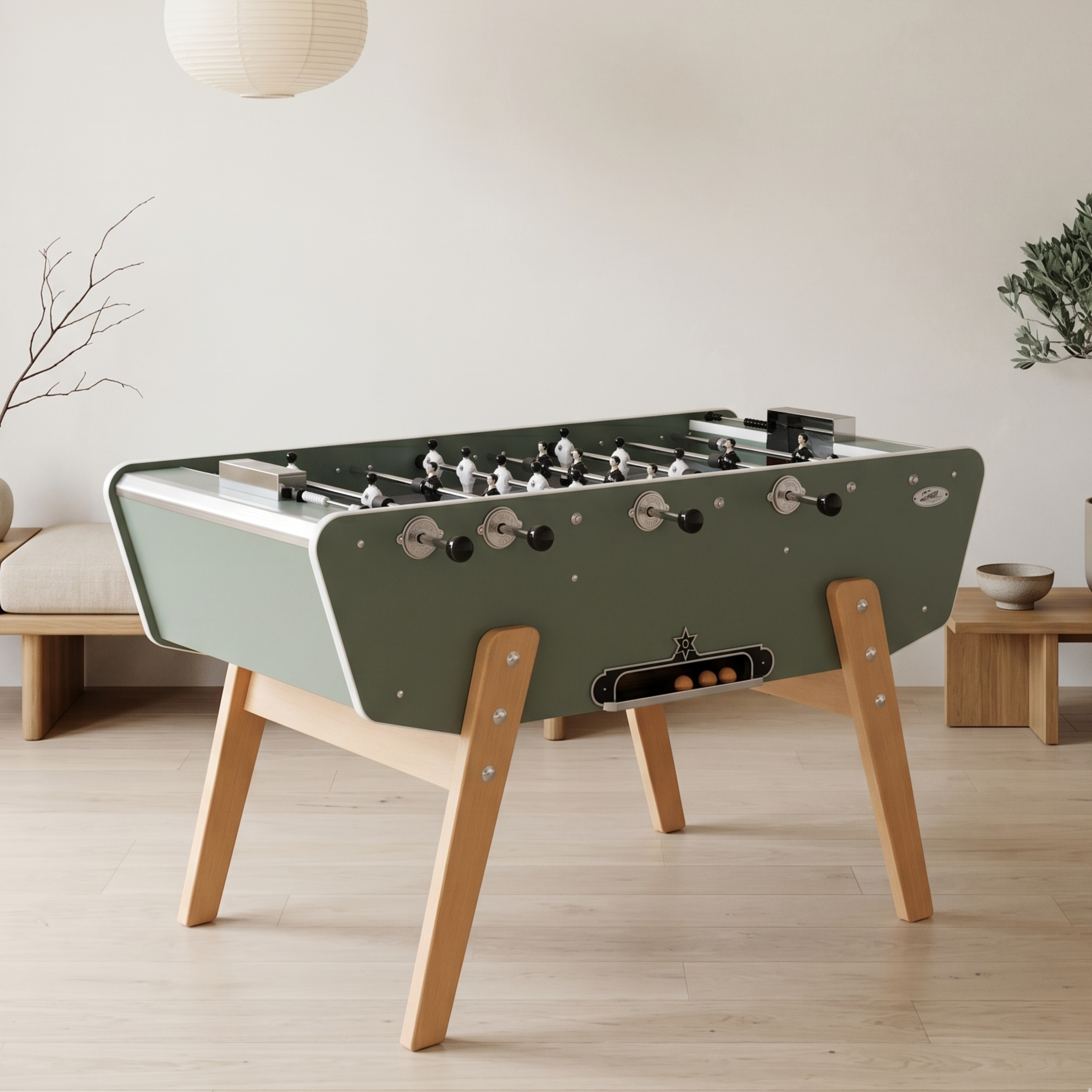 Baby-foot Stella Star vert eucalyptus installé dans un salon contemporain, édition tendance avec caisse style bateau et pieds en hêtre pour une décoration intérieure élégante et moderne.